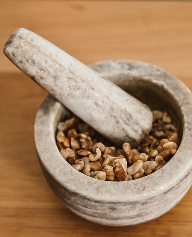 chopped walnuts sit in a stone mortar and pestal