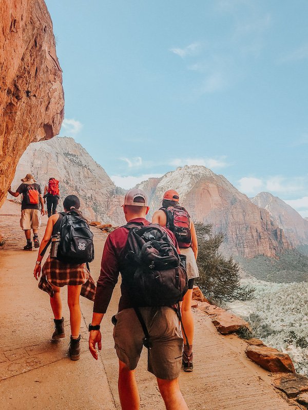 Group of hikers wearing backpacks ascends Angels Landing trail at Zion National Park