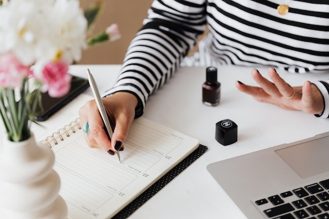 someone using a daily planner effectively while painting their nails