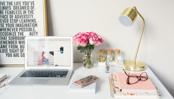 Photo of a white desk with a daily planner and laptop