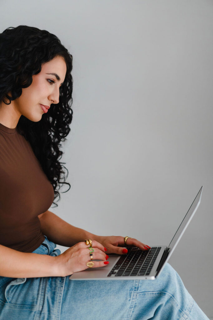 Girl sits on a stool and works on a Macbook air laptop in a photo studio | Lifestyled By Sofia