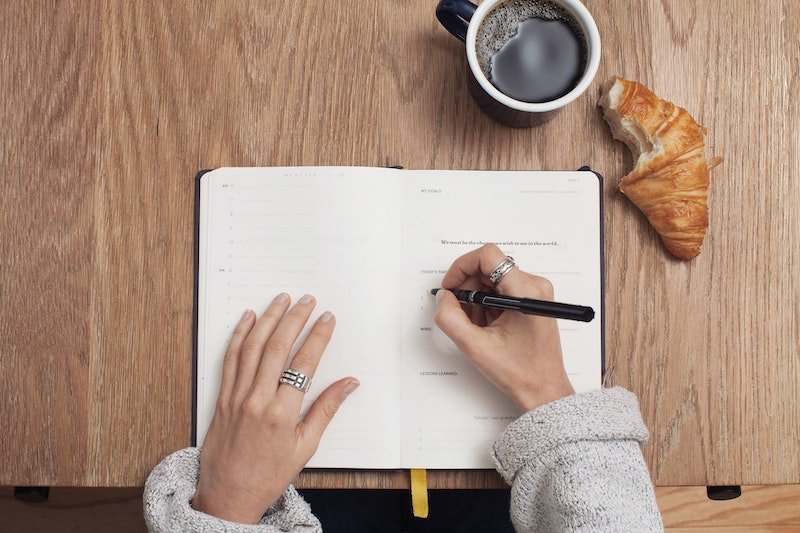 Woman writing in daily planner on desk