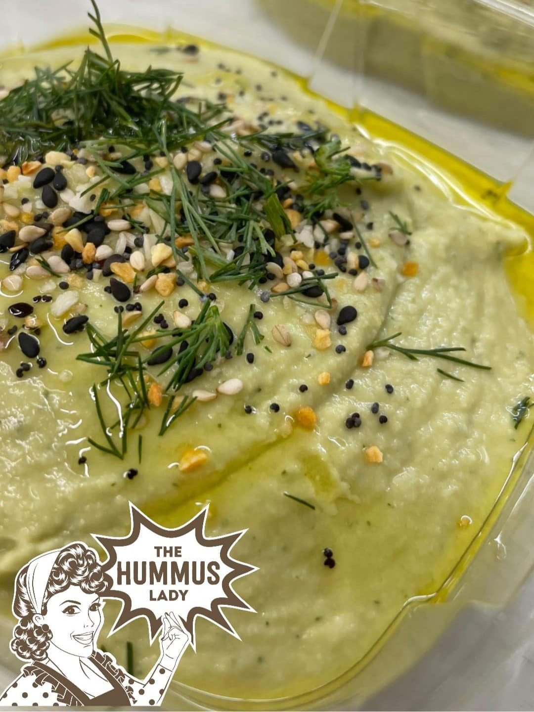 Container of deli dill pickle hummus topped with multi colored sesame seeds and fresh dill herb | Made by The Hummus Lady Pensacola