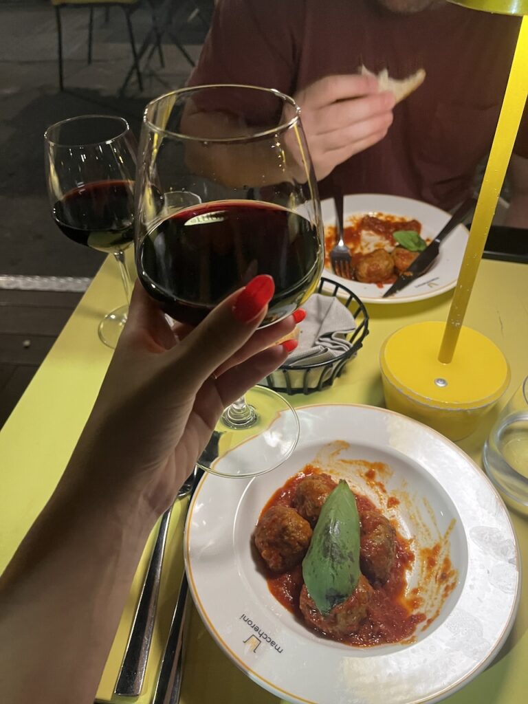 Glass of red wine and a plate of meatballs at a restaurant in Milan, Italy