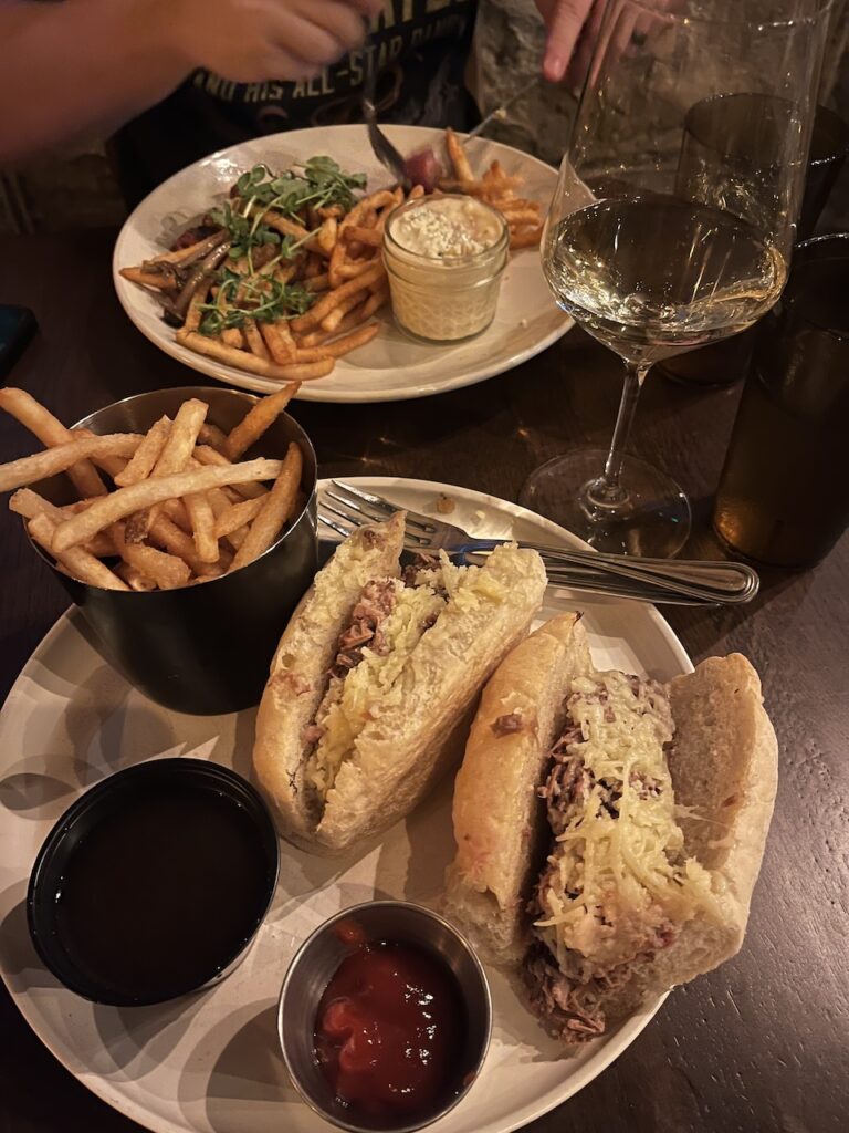 Plate with a Smoked Brisket French Dip sandwich and bowl of fries at The Burrow in East Hill Pensacola FL