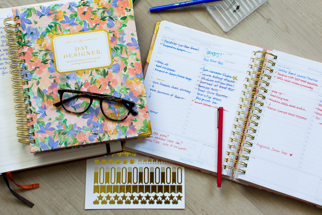 Floral print Day Designer planner sits next to open page of daily planner on top of a gold sticker sheet | Lifestyled By Sofia
