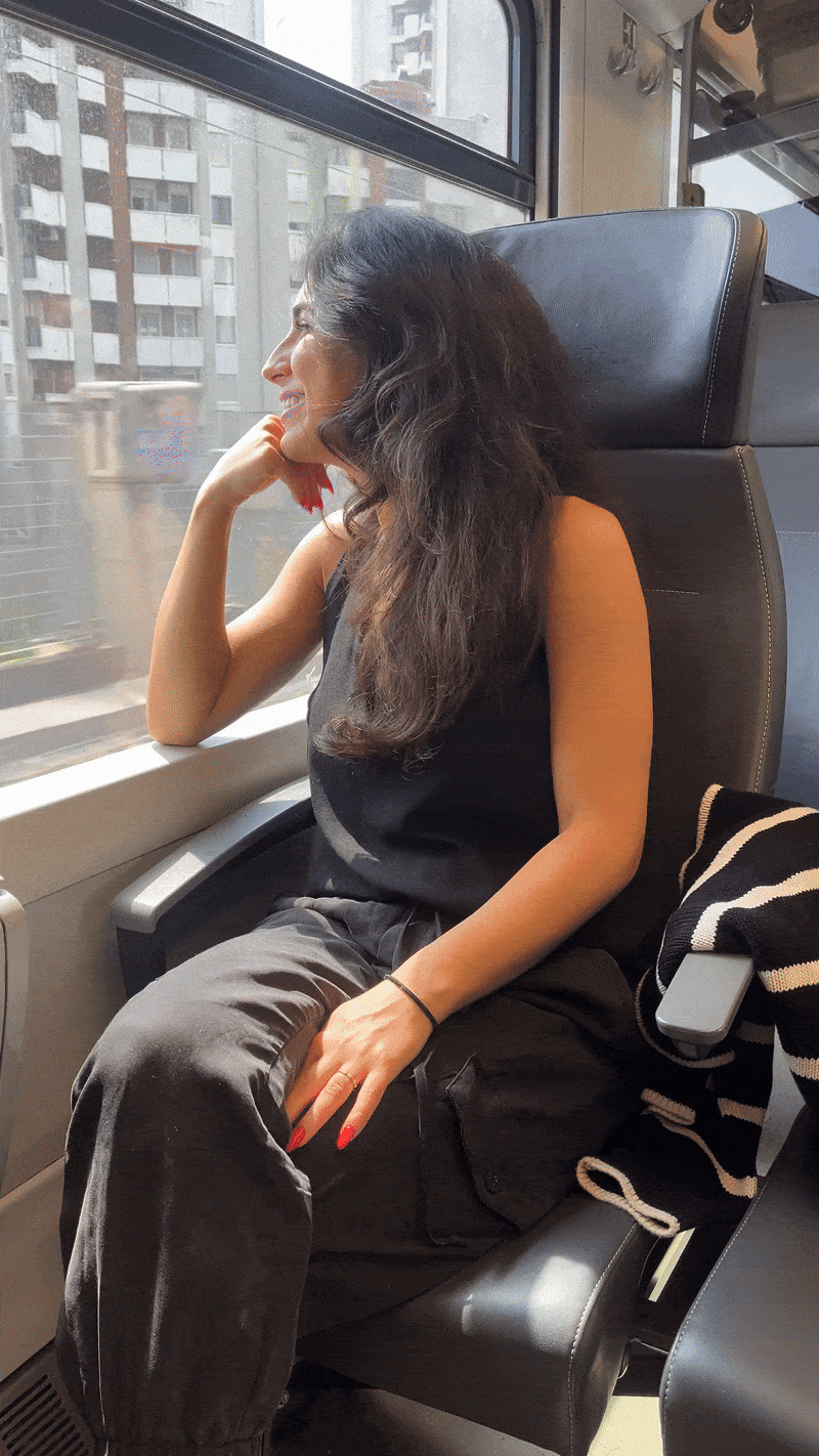 Girl sits at a window seat on a train and looks out the window at the passing town | Traveling northern Italy by train 