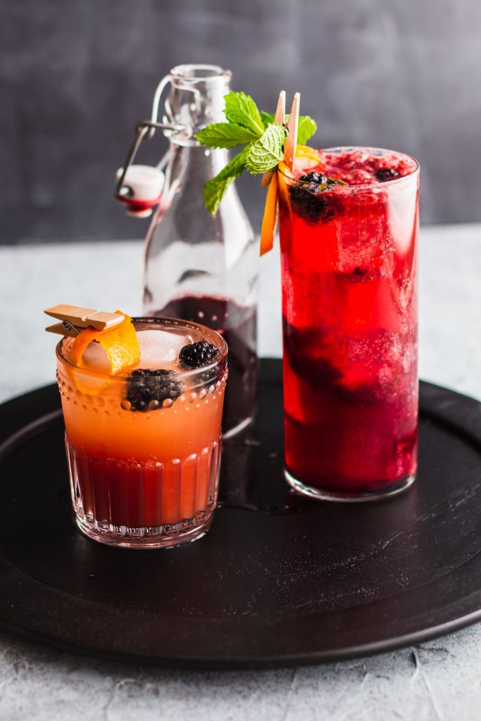 Short and tall glasses sit on a black track holding Vanilla Earl Grey Blackberry Mocktail | Festive Thanksgiving Mocktails roundup by Lifestyled By Sofia